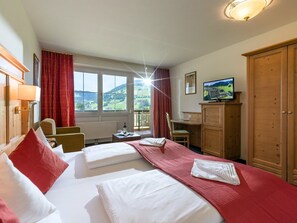 Een hotelkamer met twee bedden, een bureau, een televisie en uitzicht op het platteland.