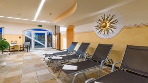 Een hotel lobby met een receptiebalie, een wachtruimte met lounge fauteuils, en een zonvormige wanddecoratie.