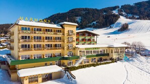 Een meerlaags hotel met balkons en een piste in de achtergrond.