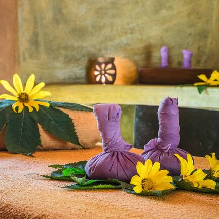 A room with a textured wall, a wooden table, and a cushion with a purple fabric.