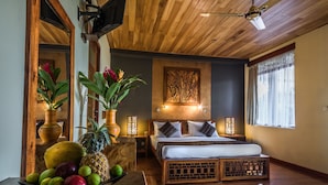 Un dormitorio con techo de madera, una cama con ropa blanca, un frutero sobre una mesa de madera y una obra de arte colgada en la pared.