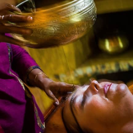 A person receiving a traditional treatment with a bowl and a spoon.