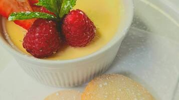 Un postre con frambuesas y hojas de menta en un bol blanco.