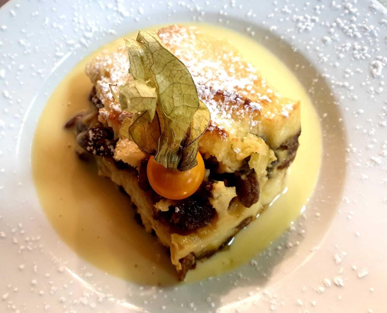 Un postre con salsa de caramelo, una cereza y una hoja como decoración en un plato.