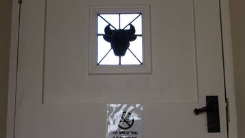 A door with a bull's head window and a no smoking sign.