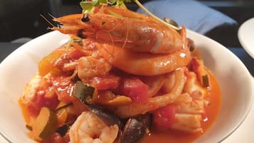 Un plato de mariscos con camarones y mejillones en salsa de tomate, adornado con hierbas.