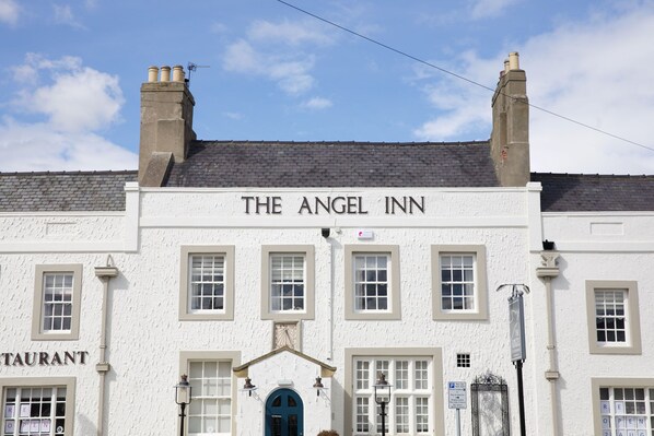 Un edificio blanco con el letrero "THE ANGEL INN" sobre la entrada.