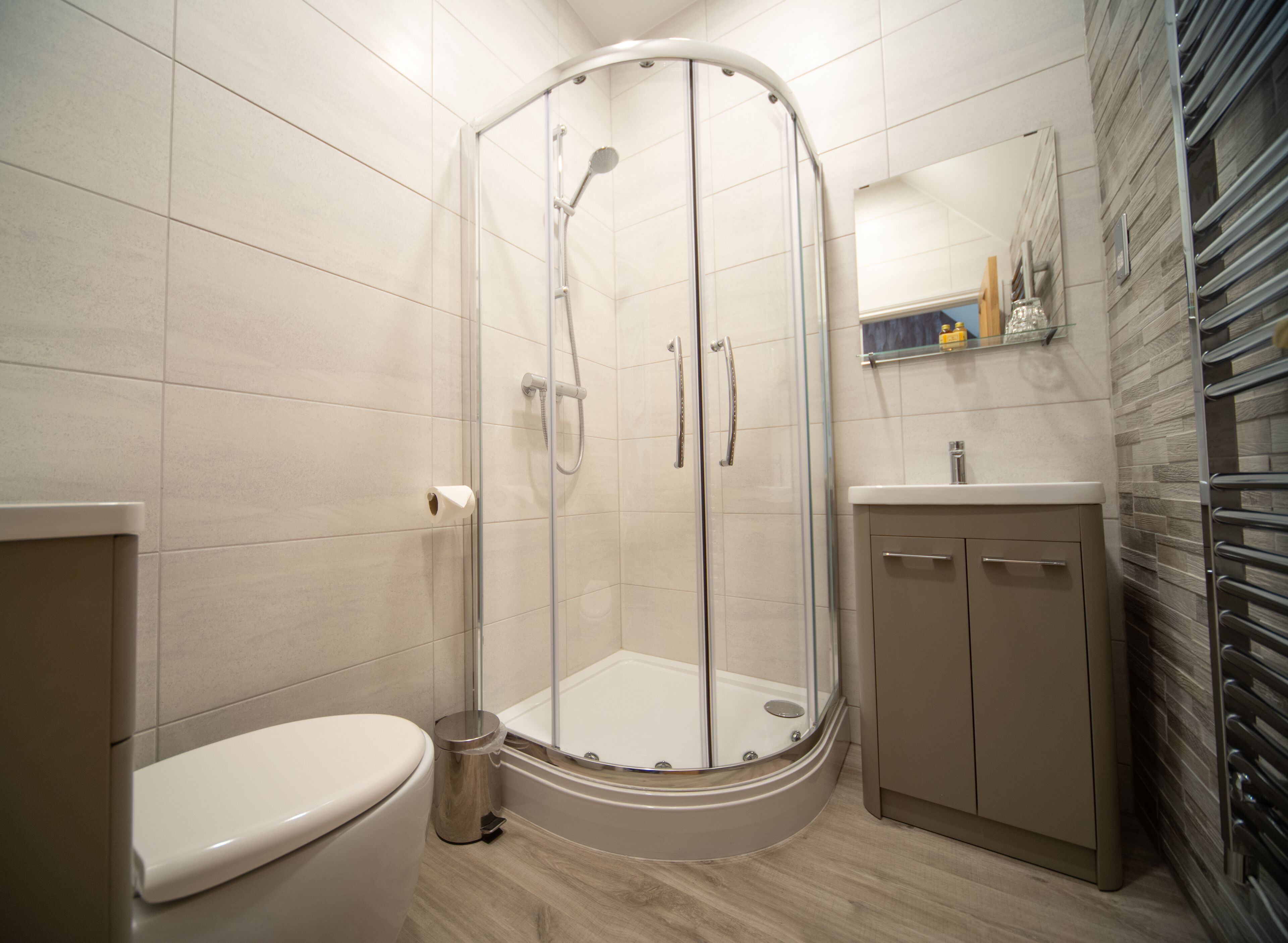 Un baño moderno con ducha envuelta en vidrio, un inodoro y un lavabo con espejo.