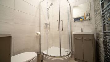 A modern bathroom with a glass-enclosed shower, a toilet, and a sink with a mirror above it.