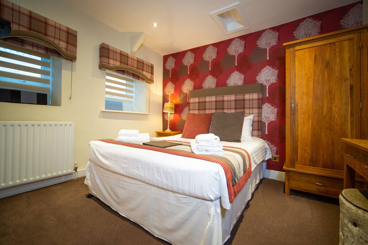 Een slaapkamer met een bed, een kast, een radiator en een raam met zonwering.