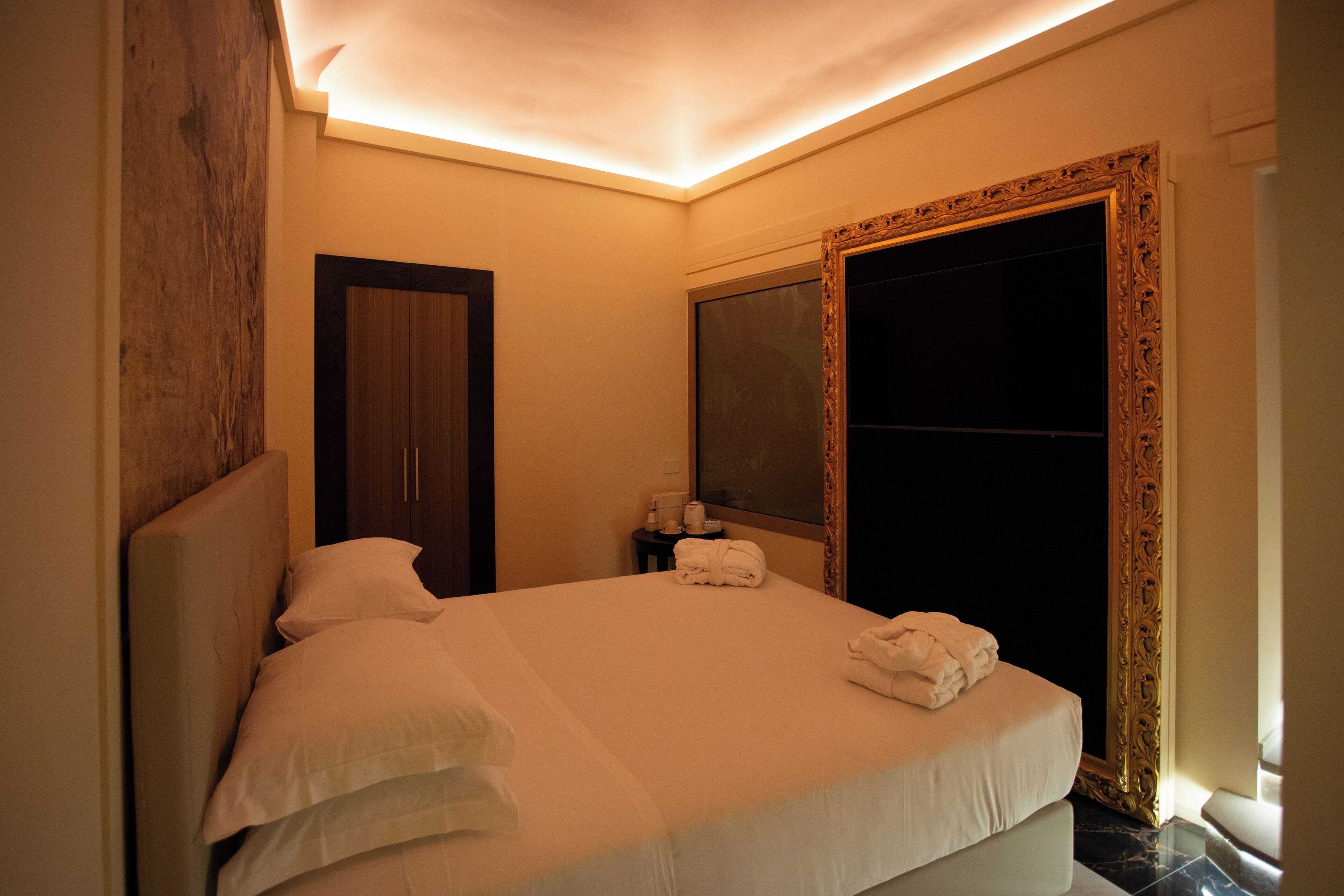 A hotel room with a bed, a nightstand, a mirror, and a wardrobe.
