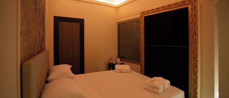 A hotel room with a bed, a nightstand, a mirror, and a wardrobe.