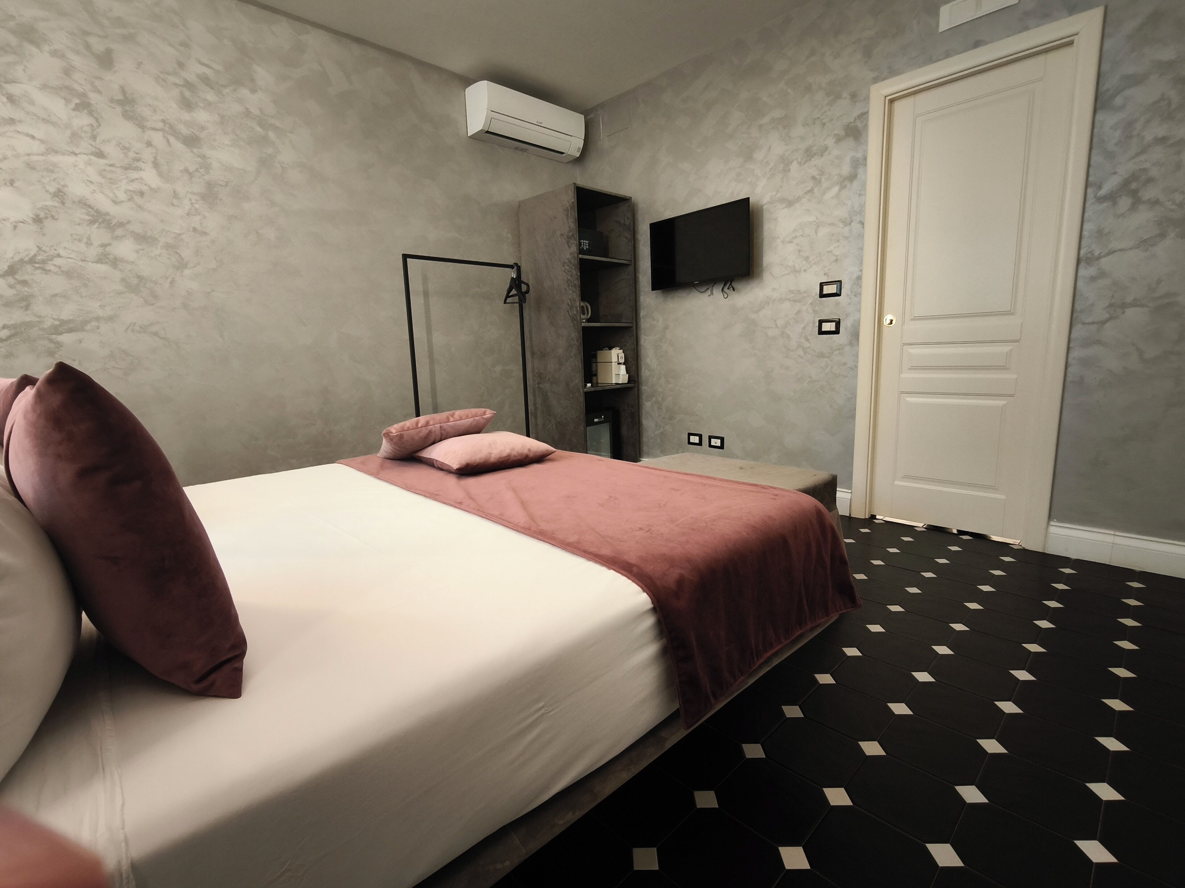 Quarto com cama, guarda-roupa, televisão e porta.