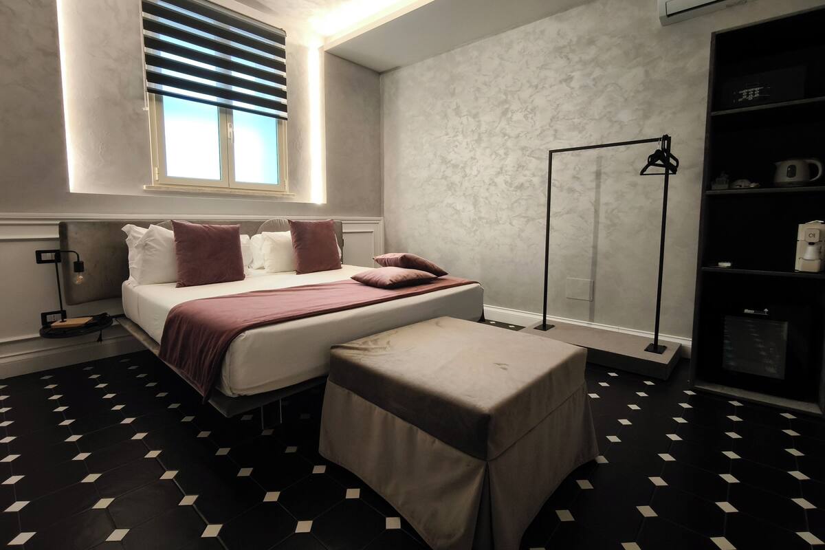 Une chambre d’hôtel moderne, équipée d’un lit, d’une table de chevet et d’un lampadaire.