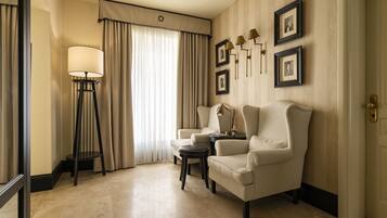 A hotel room with a large window, two armchairs, a floor lamp, and a small table.