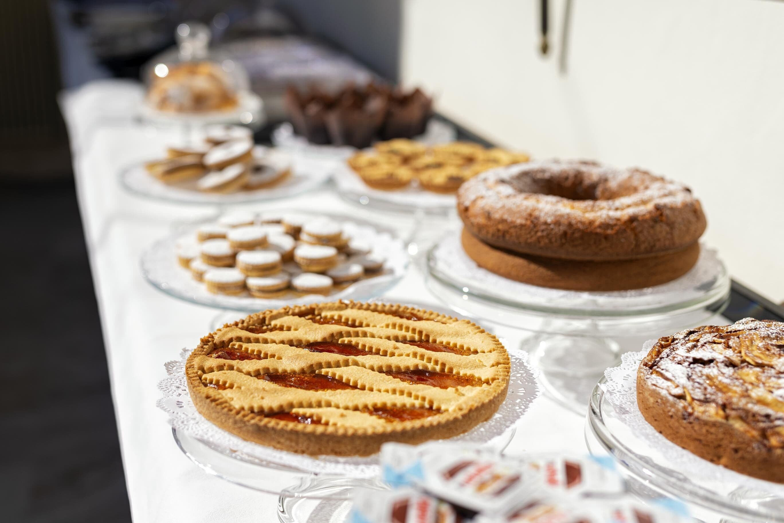 A variety of desserts on display, including pies, tarts, and cakes, arranged on a table.