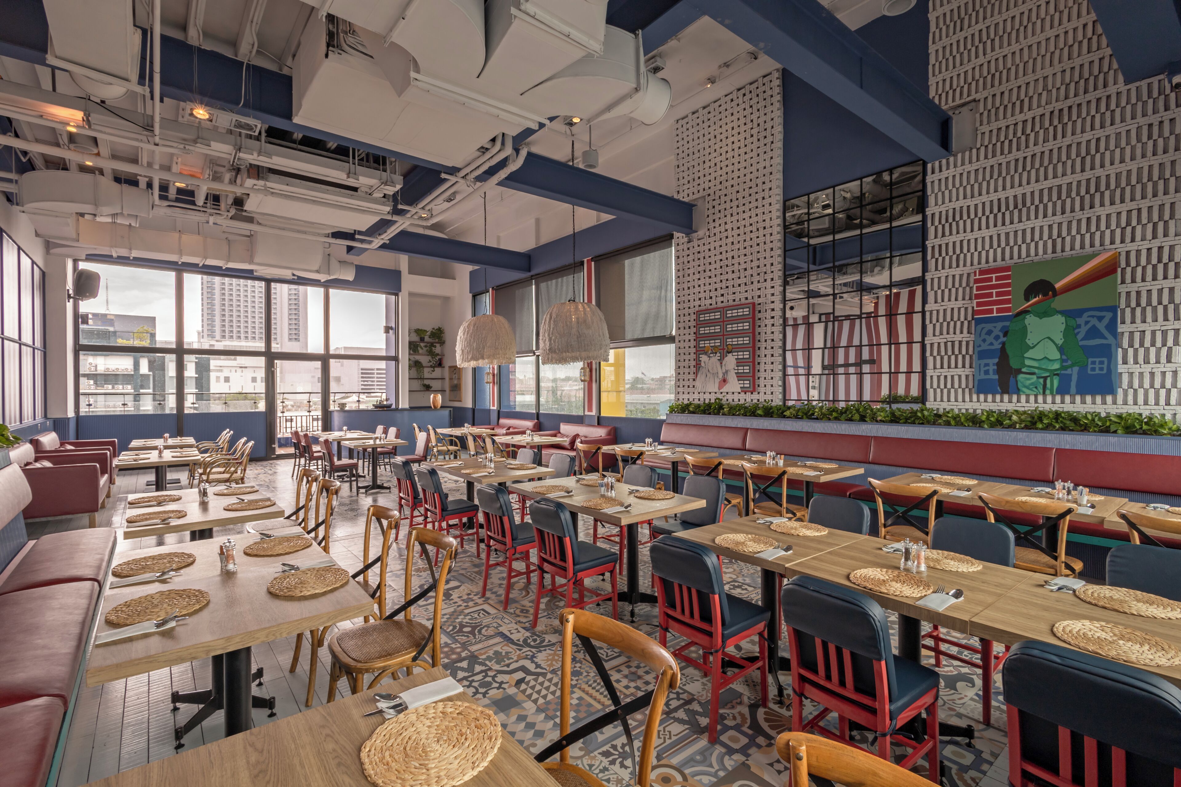 A restaurant interior with multiple dining tables, chairs, and a high ceiling with exposed ductwork.