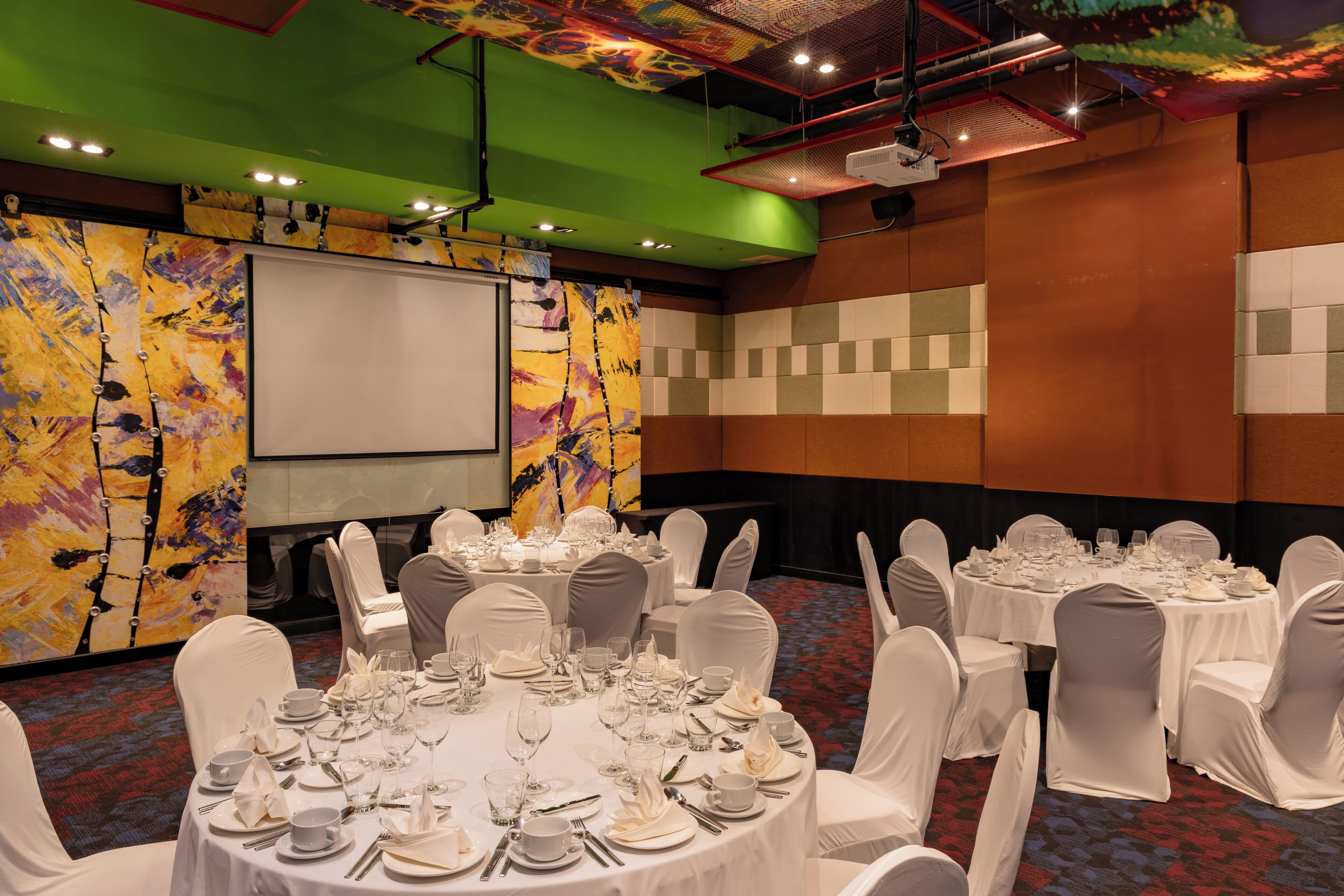 A conference room with multiple tables set for a meeting, equipped with chairs and a projector screen.