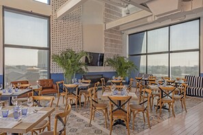 A restaurant with high tables and chairs, large windows, and decorative wall panels. - Siam@Siam Design Hotel Pattaya (Pattaya)