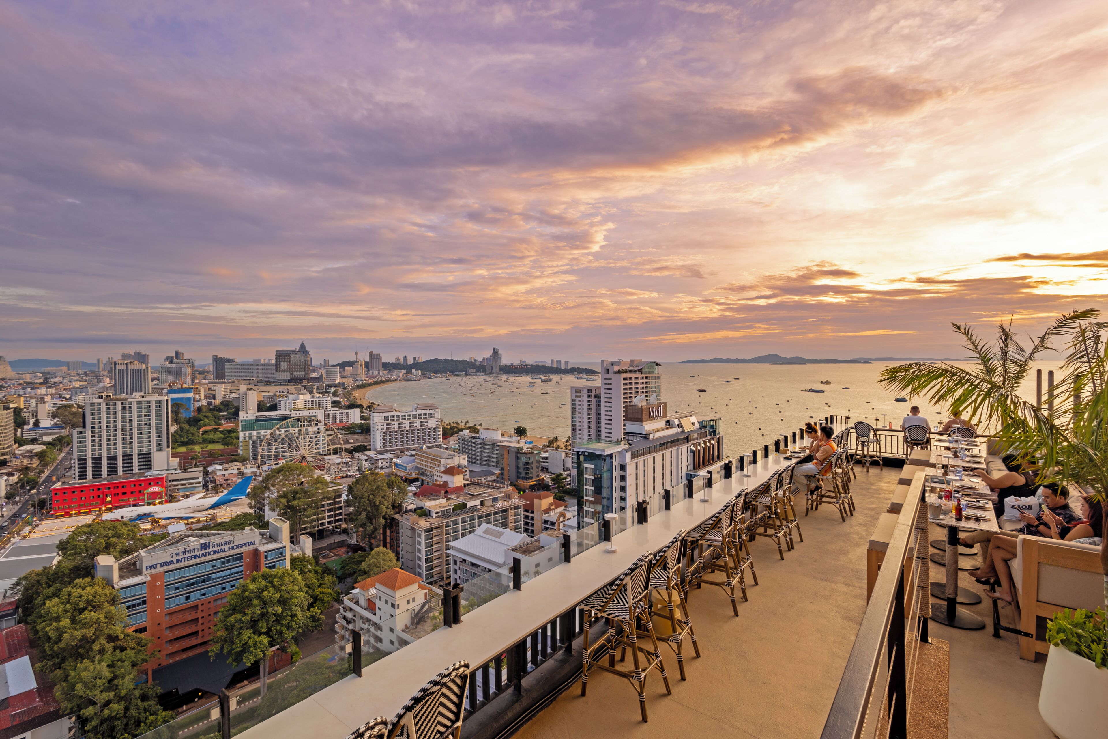 A coastal cityscape with a view of the beach, hotel buildings, and a Ferris wheel.