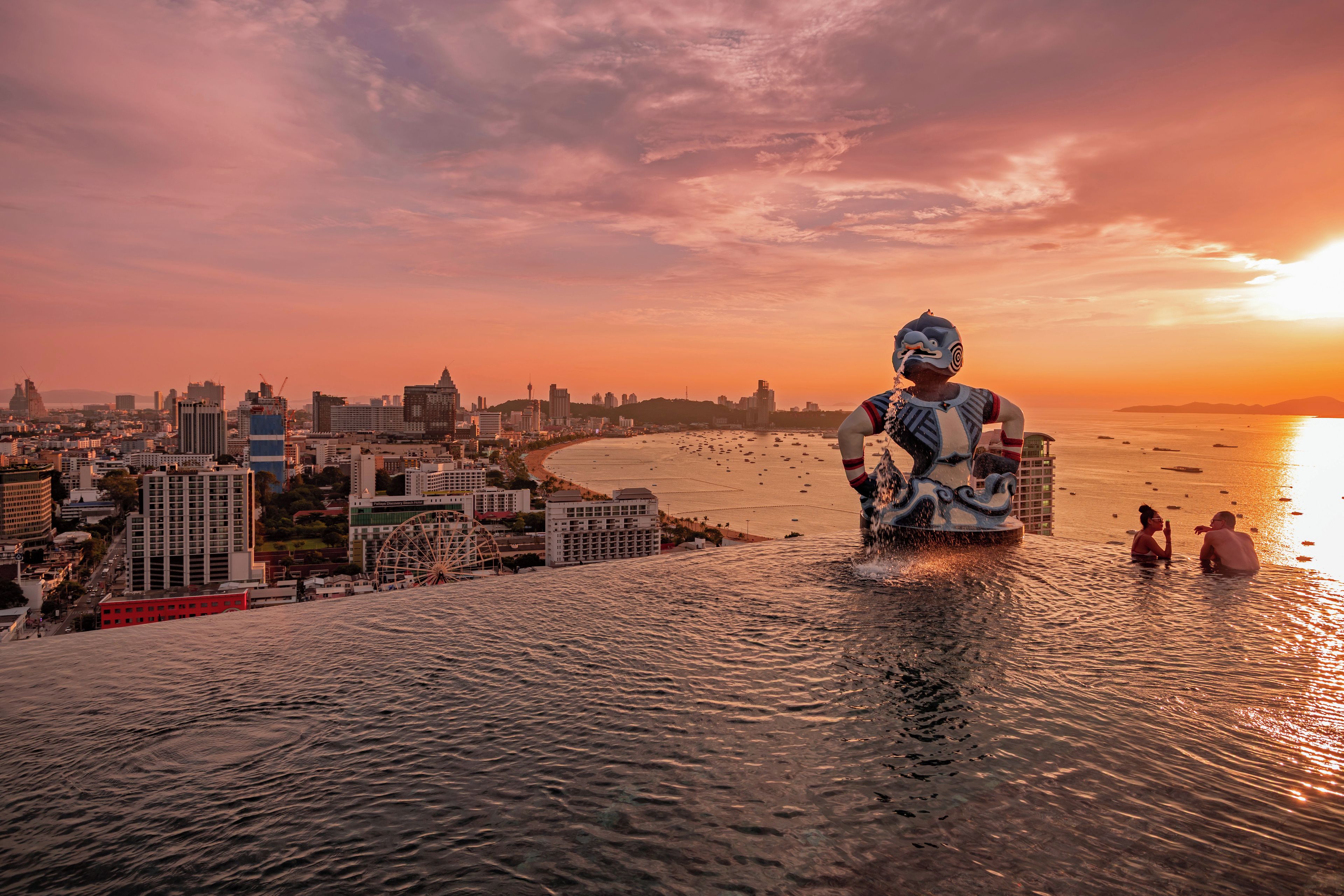 A statue in a body of water with a cityscape in the background.