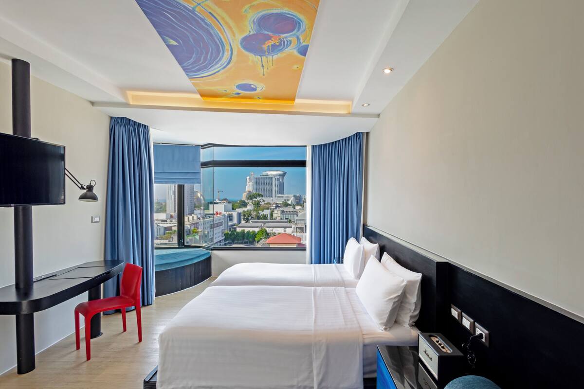 Una habitación de hotel con una cama, un escritorio, una silla y un televisor.