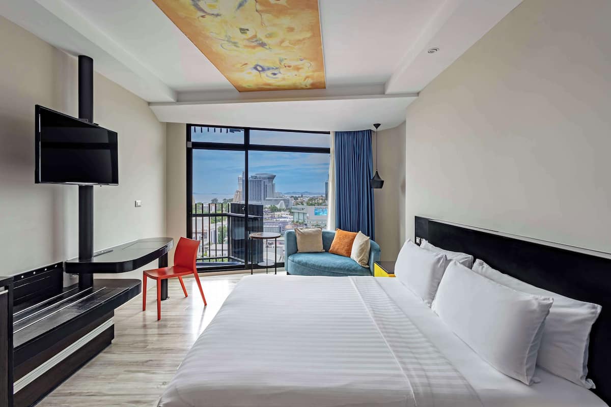 Enjoy a city view from the comfort of a spacious bed, with a flat-screen TV and seating area nearby.