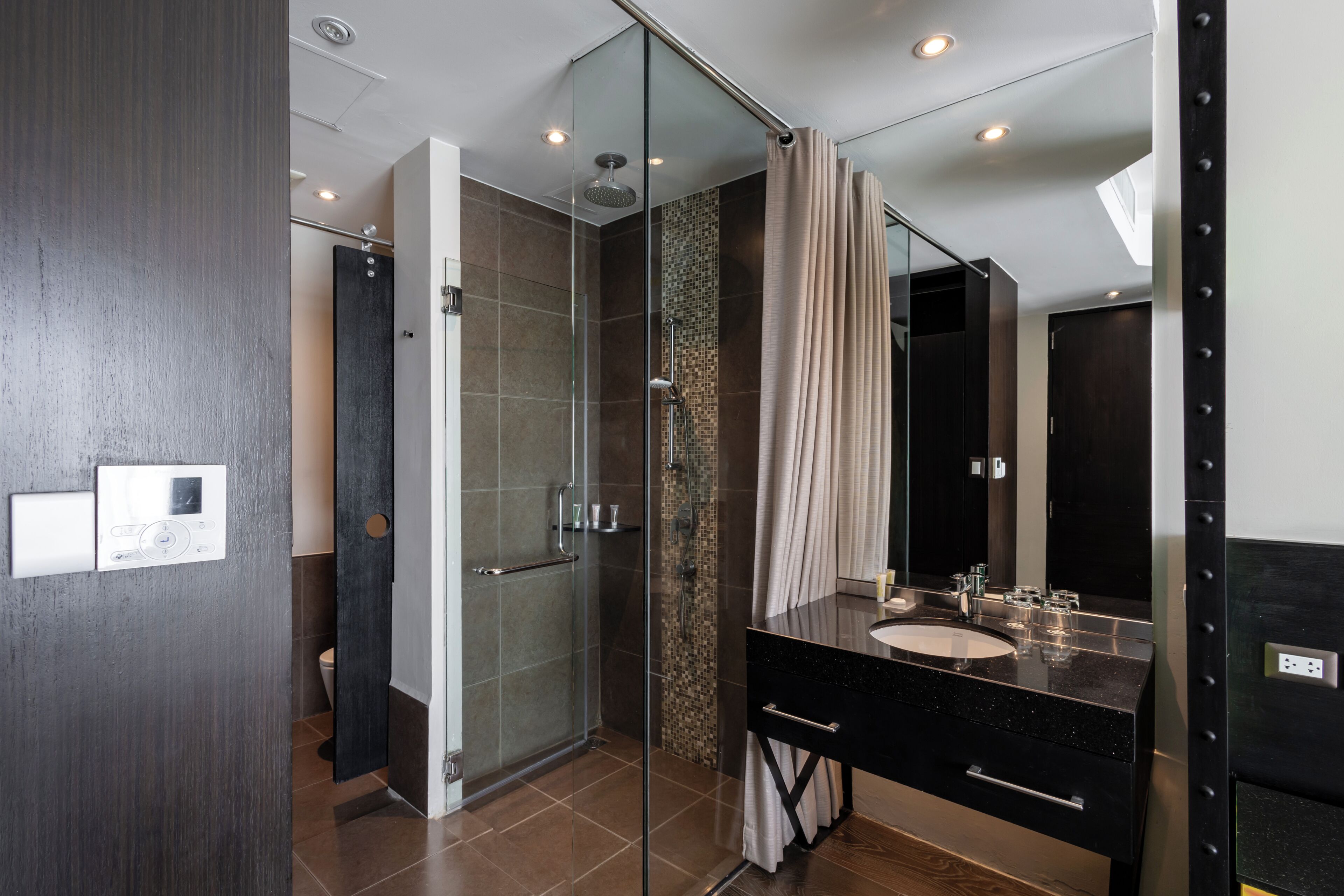 A modern bathroom with a glass shower enclosure, a black vanity with a sink, and a large mirror.