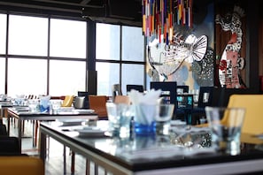 Enjoy dining in style with a long table set for a memorable meal, surrounded by elegant glassware and a beautiful piece of art.