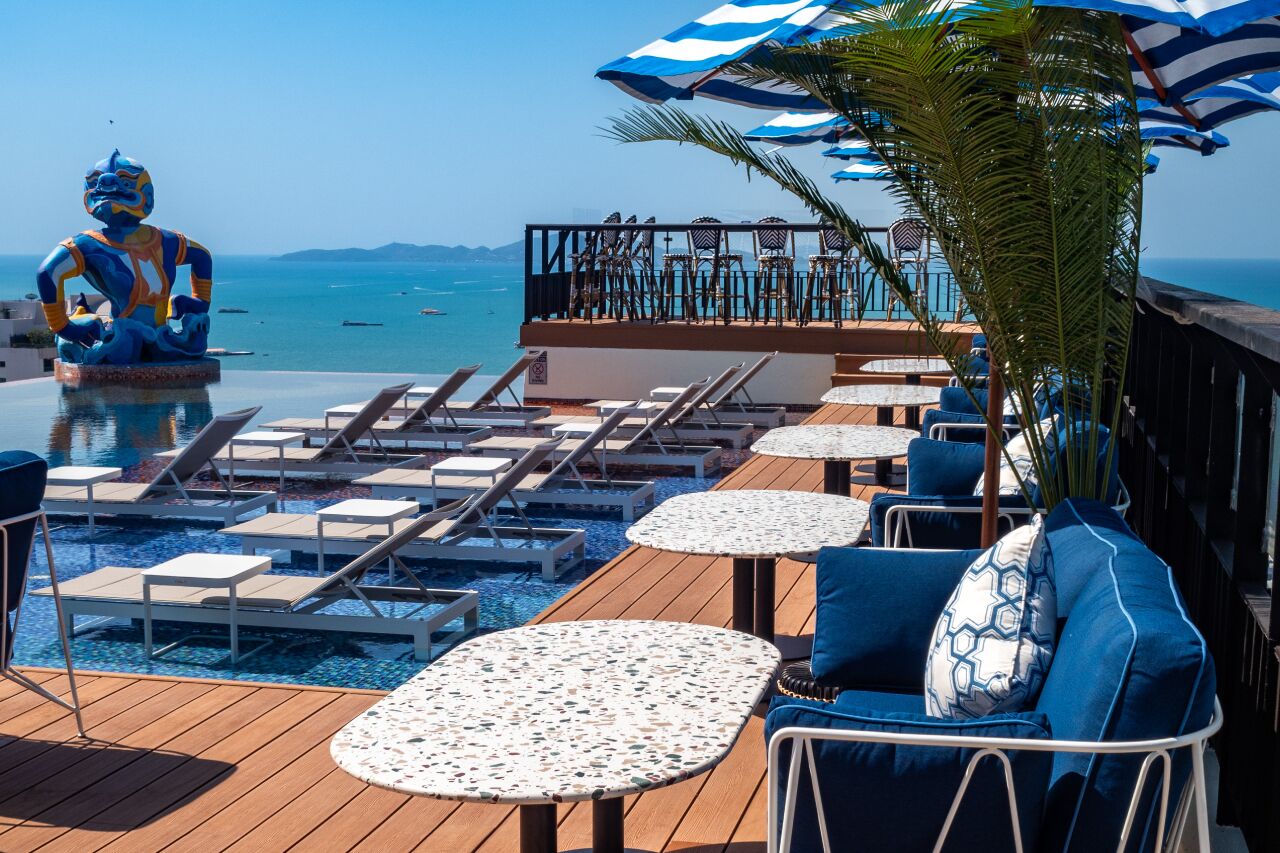 A poolside area with lounge chairs, tables, and a decorative statue.