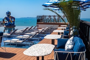 A poolside area with lounge chairs, tables, and a decorative statue. - Siam@Siam Design Hotel Pattaya (Pattaya)