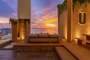 A modern interior with a sofa and wooden benches, a view of the sunset, and a vertical garden. - Siam@Siam Design Hotel Pattaya (Pattaya)