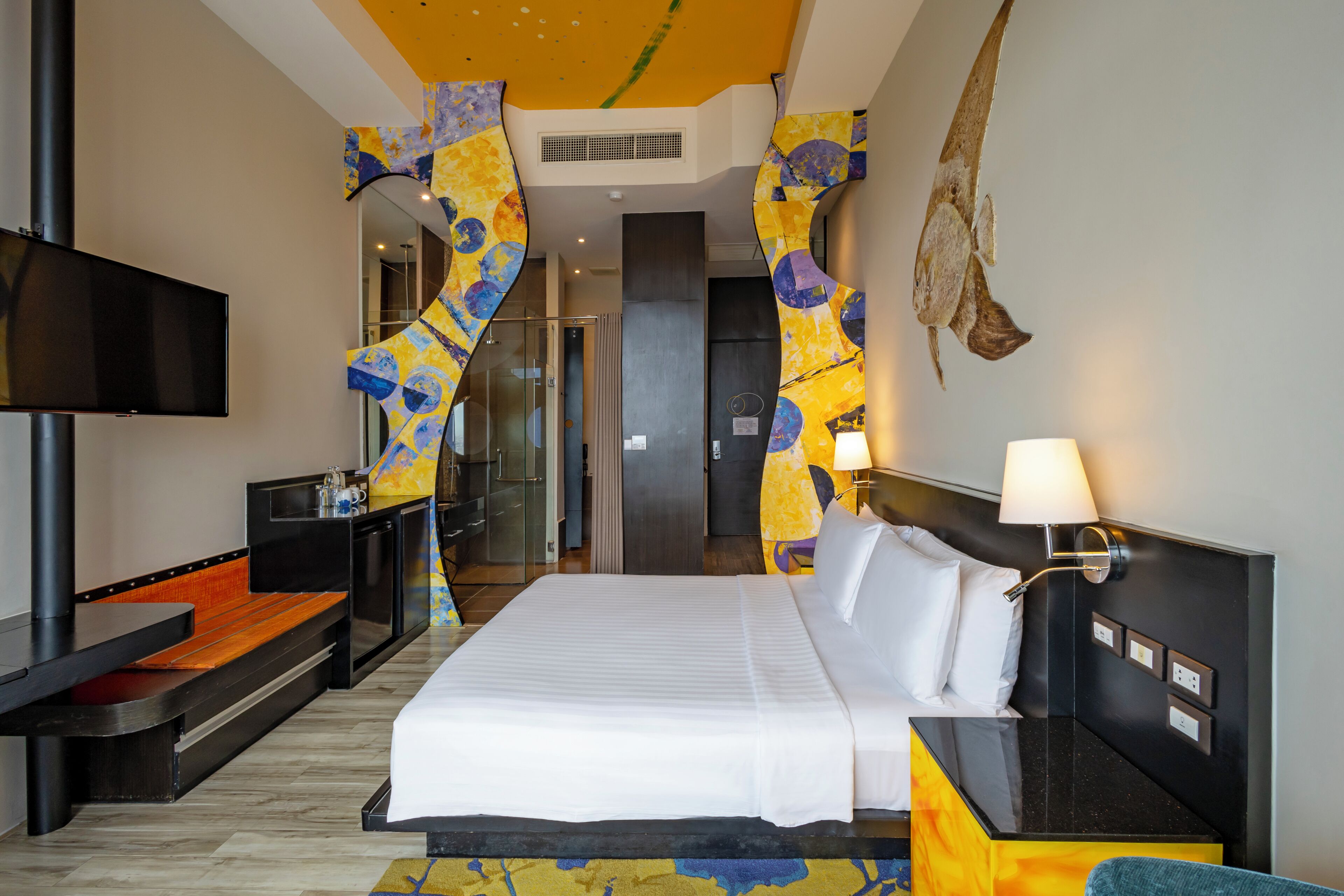 A hotel room with a bed, a TV, a desk, and a bathroom.