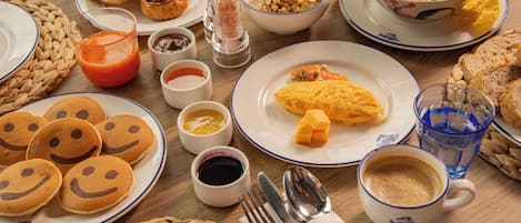 A breakfast table with various dishes including pancakes, eggs, and soup.