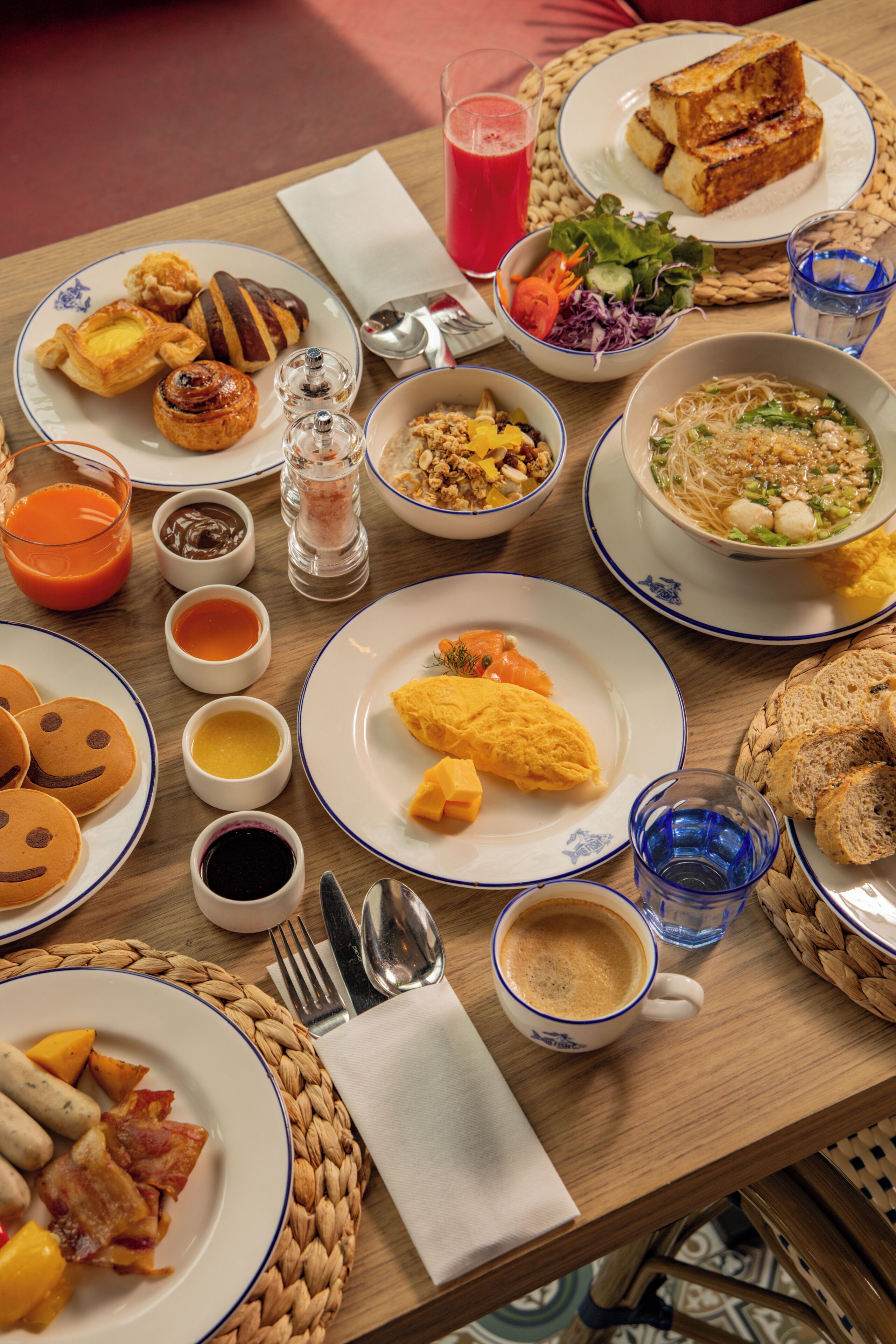 A breakfast table with various dishes, including pancakes, eggs, and a bowl of soup.