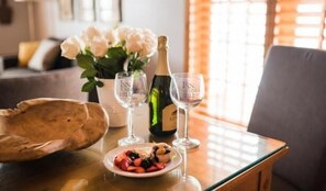 A table with a bottle of champagne, two glasses, a plate of fruit, and a vase of flowers. - Inn on Summer Hill (Santa Barbara)