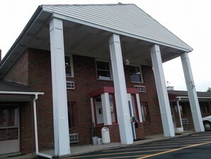 A brick building with a covered porch supported by white columns.