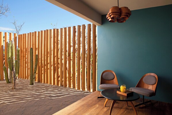 A modern room with a wooden floor, two wooden chairs, a small table with a tray of items, and a blue wall.