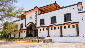 Un edificio histórico con fachada blanca, marcos de ventana negros y un patio empedrado.