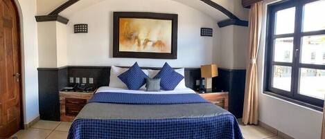 Una habitación de hotel con una cama, un cuadro, una ventana y una puerta.
