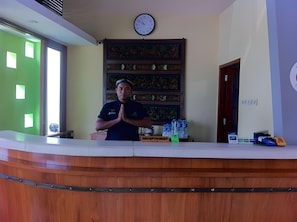 Un mostrador de recepción con un reloj, un dispensador de agua y un cartel que dice 'RECEPTIONIST'.