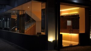 A modern hotel entrance with glass doors, a visible staircase, and warm interior lighting. - Dermaga Keluarga Hotel (Yogyakarta)