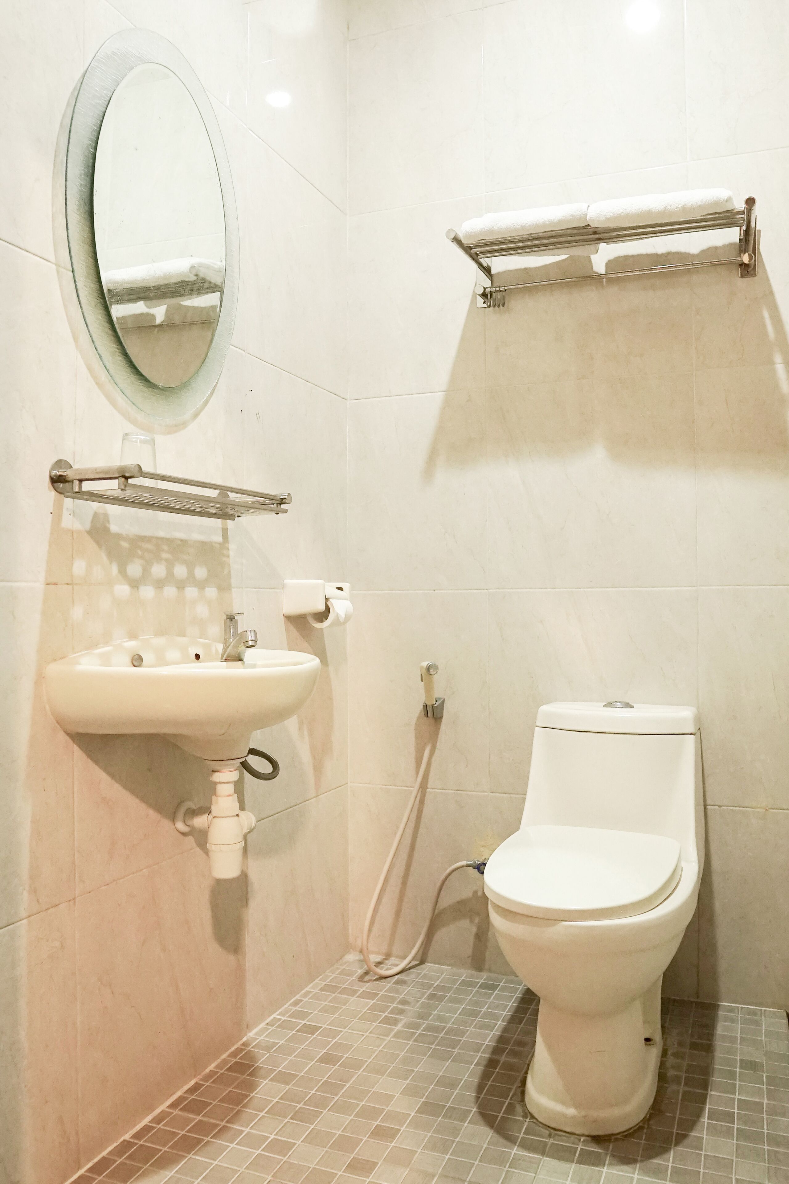 A bathroom with a sink, mirror, toilet, and towel rack.