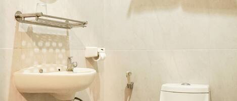 A bathroom with a sink, mirror, toilet, and towel rack.