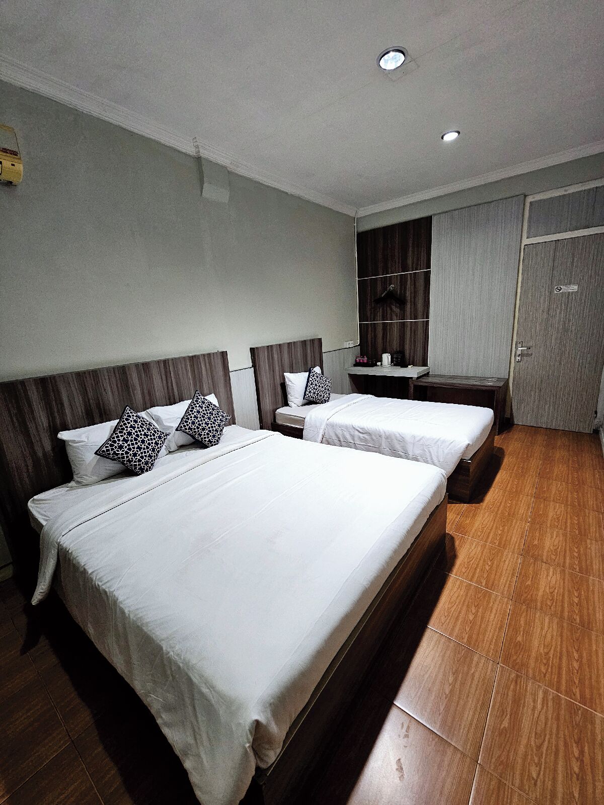 Habitació d'hotel amb dos llits, un armari de fusta, una taula petita i un mirall.