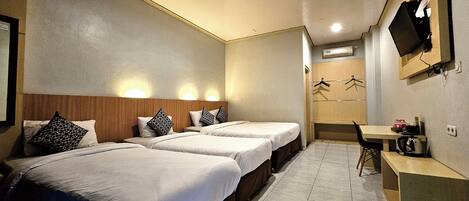 A hotel room with two beds, a desk, a chair, a TV, and a wardrobe.