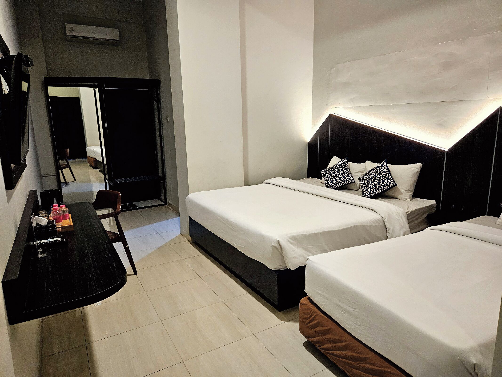 Une chambre d’hôtel avec deux lits, un bureau et une chaise.