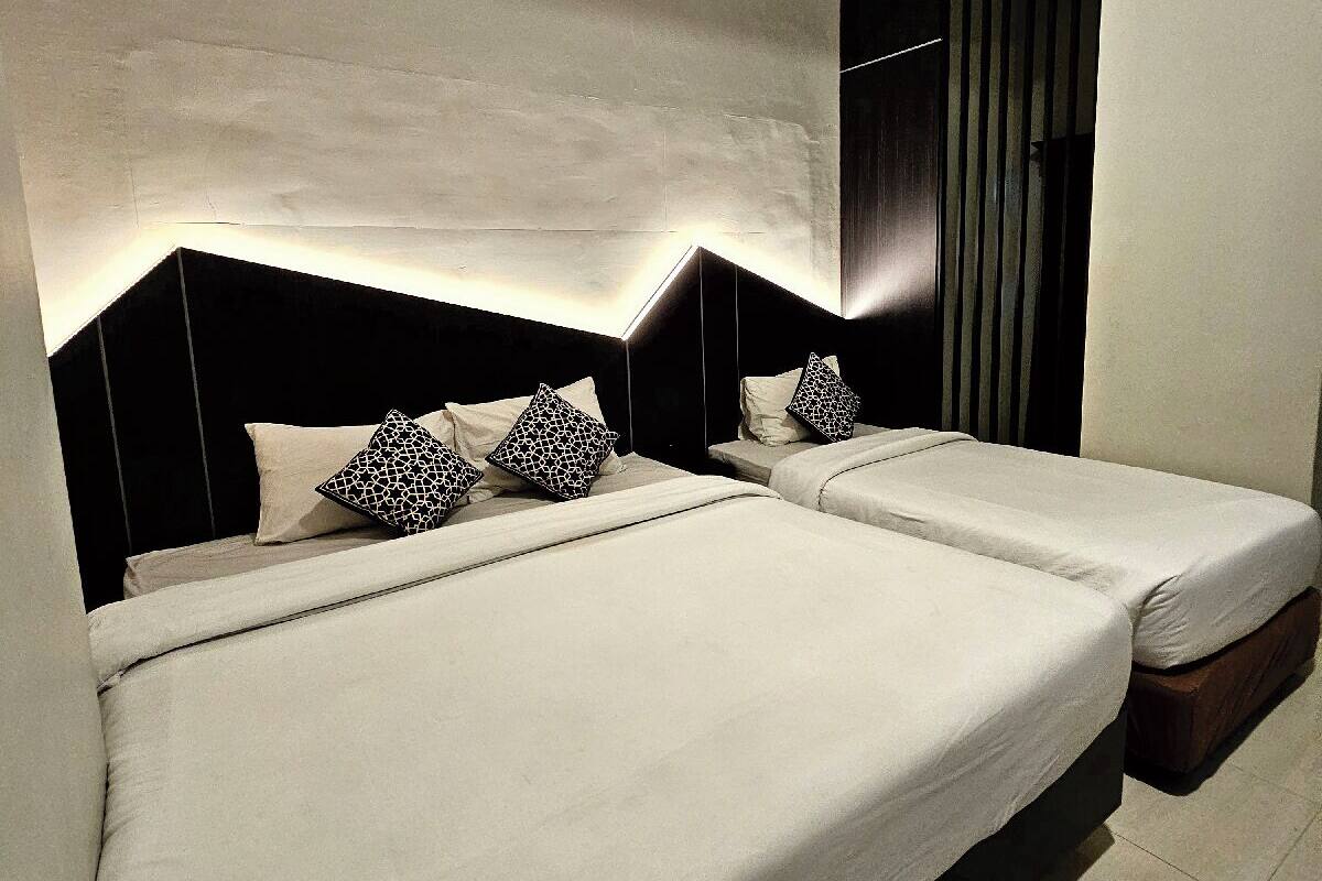 Ett modernt hotellrum med två sängar, ett stort fönster med persienner och en minimalistisk inredning.