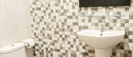 A bathroom with a tiled floor, a toilet, a sink, and a mirror.