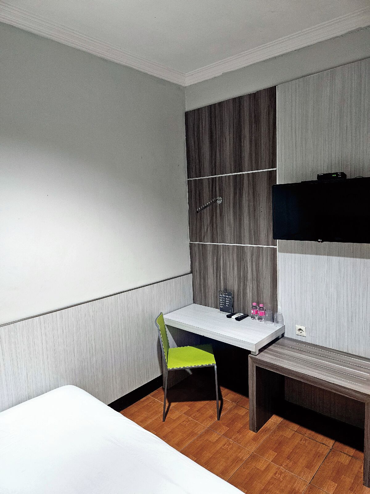 Una camera da letto moderna e accogliente con un letto, una scrivania, una sedia e un televisore a parete.